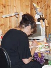 Eine Person sitzt an einem Tisch und malt Gartenzwerge im Atelier.
