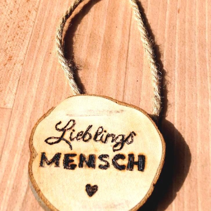 Holzscheibe mit der Gravur "Lieblings Mensch" und einer Schnur zum Aufhängen.